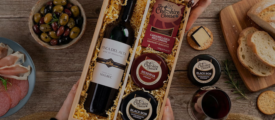 Cheese gift hamper with waxed truckles, biscuits, and a bottle of wine