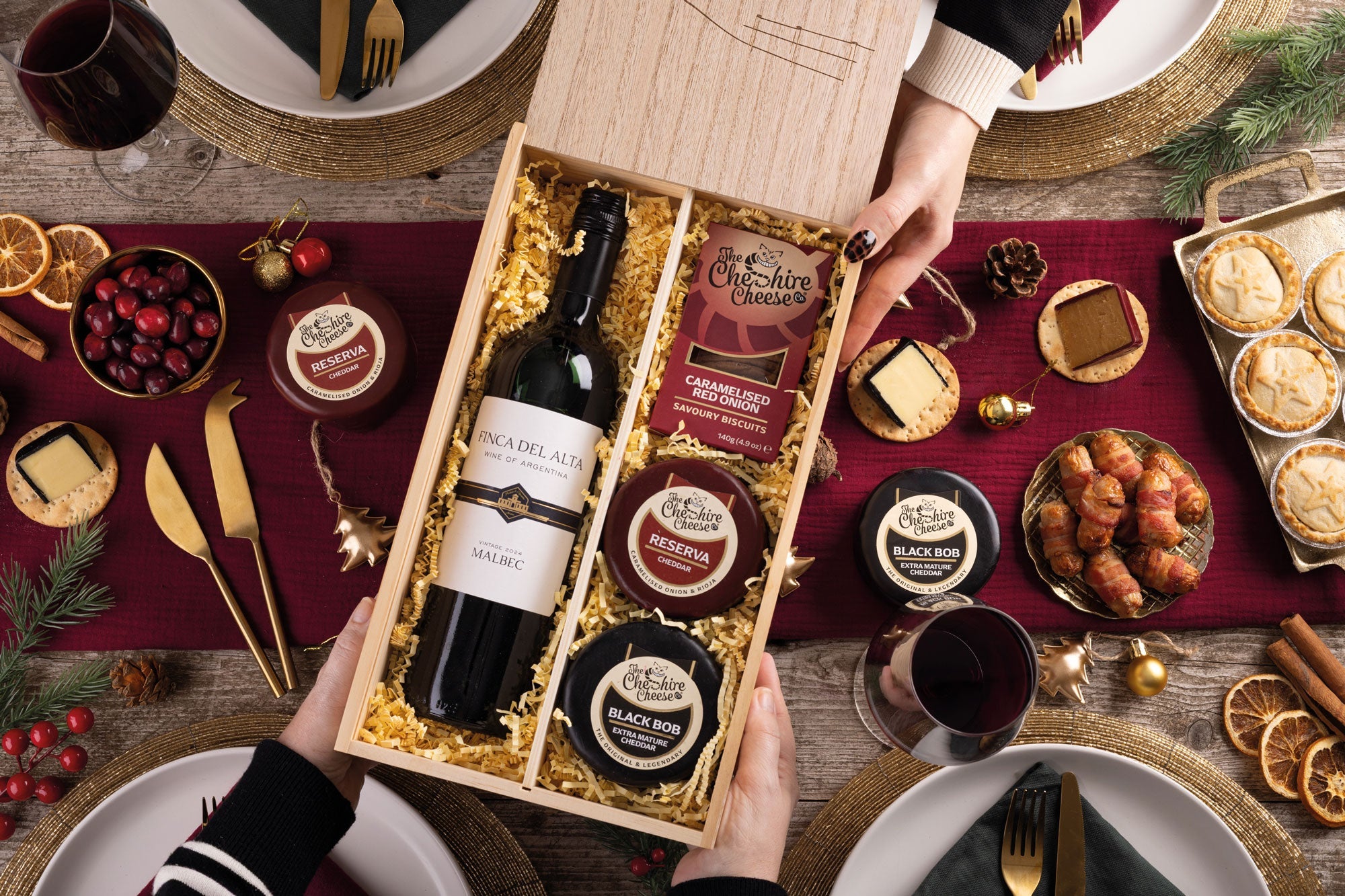 Christmas cheese hamper with waxed truckles, bottle of red wine and festive accompaniments